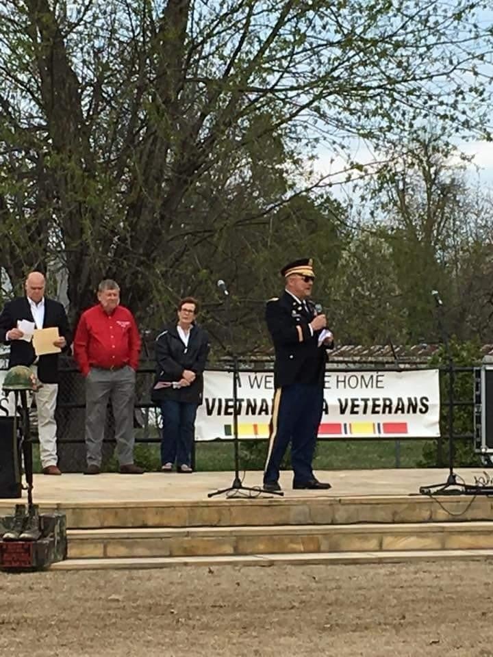 a person stand on an outdoor stage and holding mike in hand