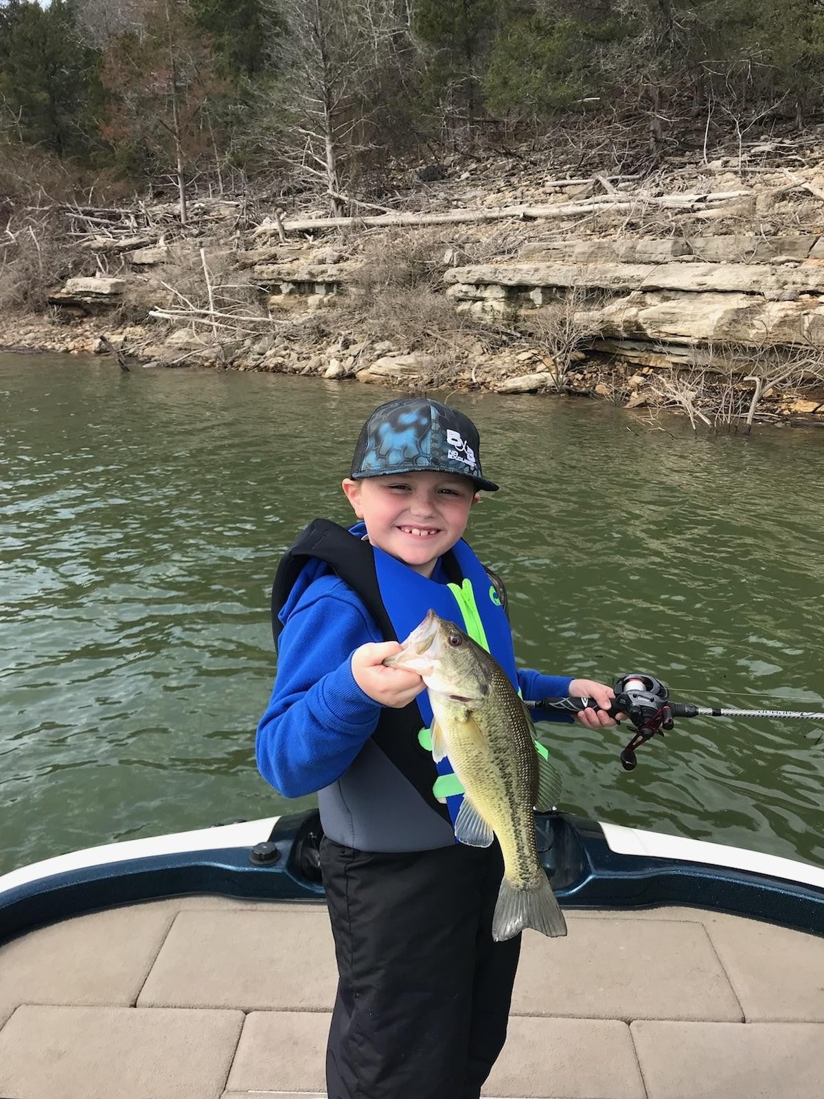 boy ona boat holding a largemouth